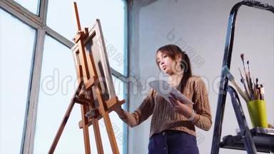 年轻女子在艺术空间用大窗户<strong>画油画</strong>